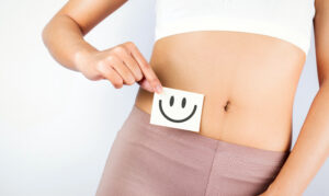 Photo of woman holding a happy face by her stomach to signify gut health