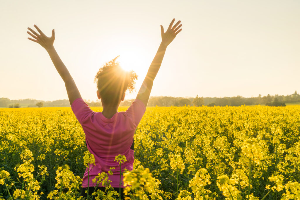 Photo of woman in a field of flowers enjoying the sunshine