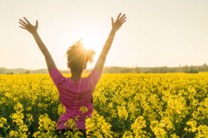 Photo of woman in a field of flowers enjoying the sunshine