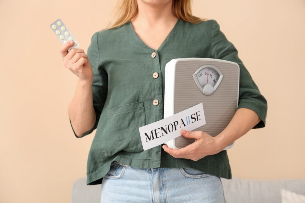 Photo of menopausal woman holding medication and a set of scales